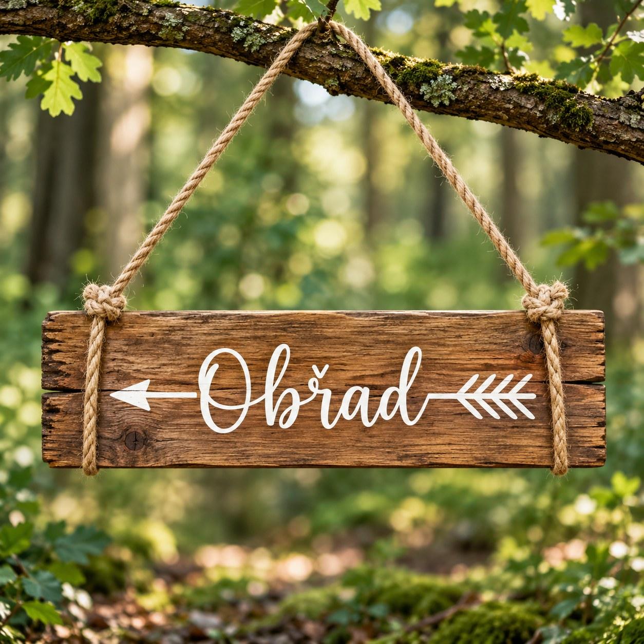 A wooden sign with an arrow reading “Obřad” (ceremony), hanging from a branch