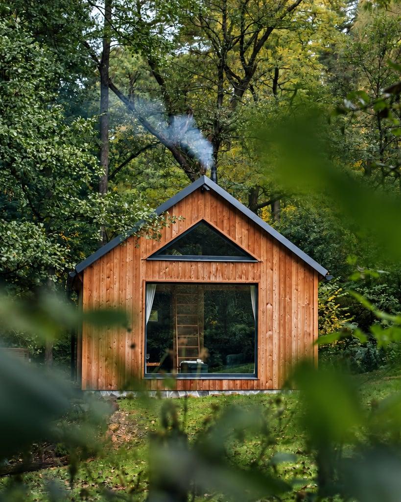 The wooden Roklinka cabin at the edge of the forest, smoke rising from the chimney